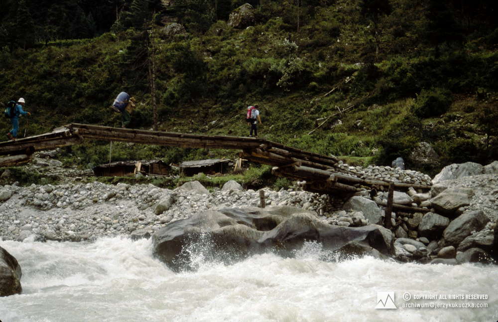 Uczestnicy wyprawy przeprawiający się przez rzekę Dudh Koshi. Przemysław Piasecki z czerwonym plecakiem.