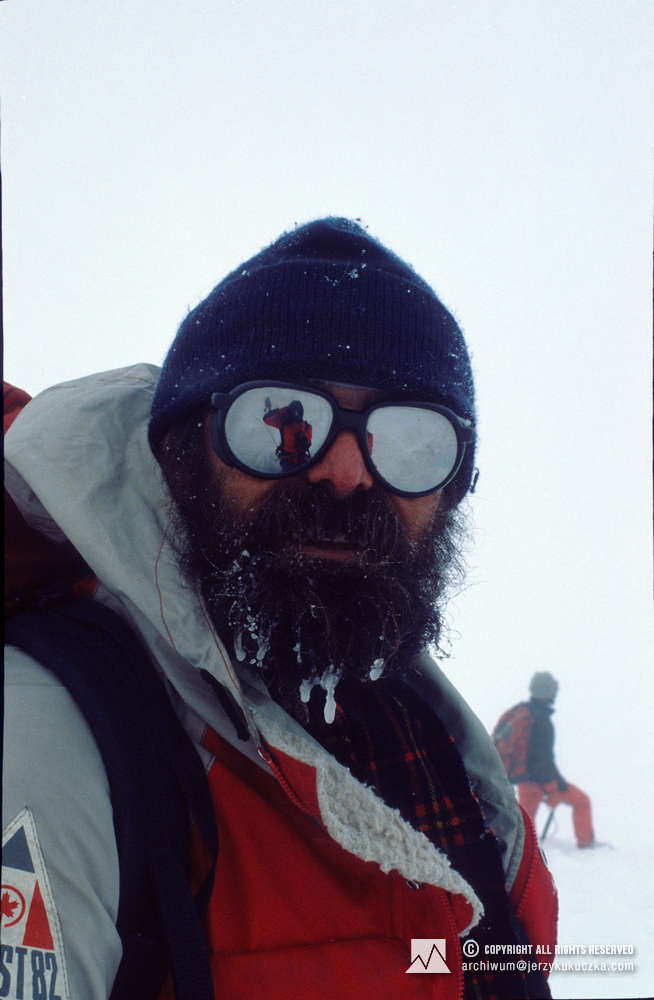 Janusz Majer na stoku Broad Peak. Za nim stoi Ryszard Pawłowski, w okularach odbija się sylwetka Jerzego Kukuczki.