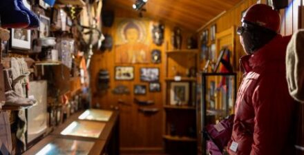 Grafika przedstawia wnętrze Izby Pamięci Jerzego Kukuczki. Widać na niej historyczny sprzęt wspinaczkowy oraz odzież himalaisty