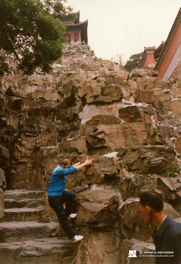 Jerzy Kukuczka próbujący się wspinać na skały przy schodach prowadzących być może do świątyni.