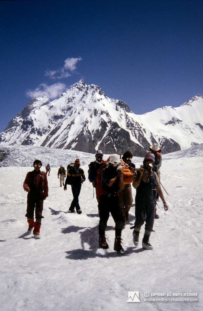 Climbers during lifting dead body of Halina Krüger-Syrokomska from K2. In the first row, the body is carried from the left by NN and Krzysztof Wielicki. In the second row from the left: Leszek Cichy and Jan Holnicki. Eugeniusz Chrobak is walking first from the left. In the background, the peaks of Kharut I (6,913 m above sea level) and Kharut II (6,805 m above sea level) are visible.