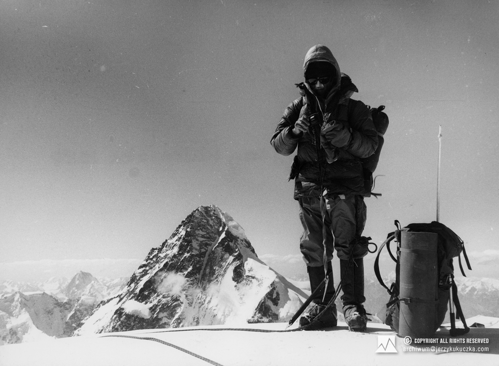 Wojciech Kurtyka na szczycie Broad Peak Central (8011 m n.p.m.). Obok plecak Jerzego Kukuczki. W tle Widoczny szczyt K2 (8611 m n.p.m.).